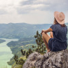 A young woman on a mountain top overlooking a river flowing between the mountains